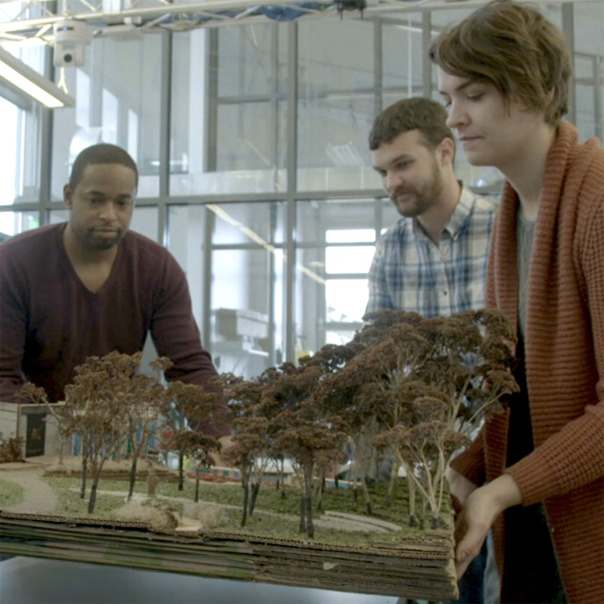 Photo of three students working together over an architectural model
